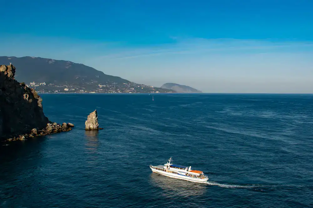 Boat cruising past steep coastal rock formations